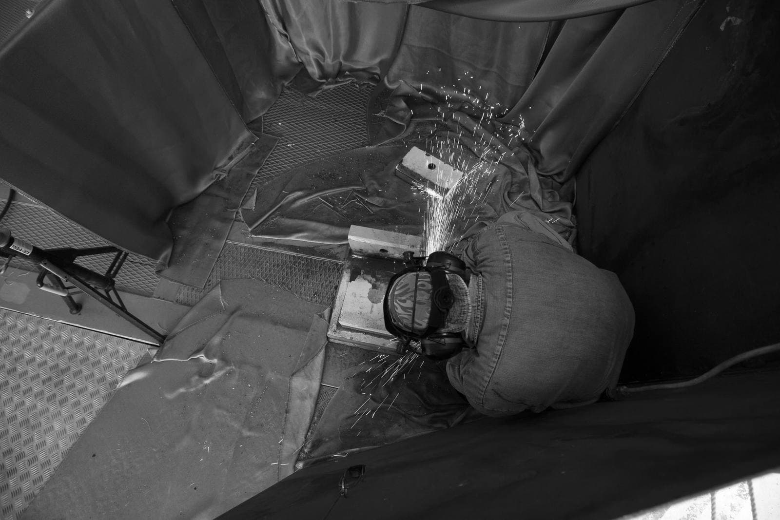 Overhead view of a welder in protective gear producing a shower of sparks while welding a steel bracket